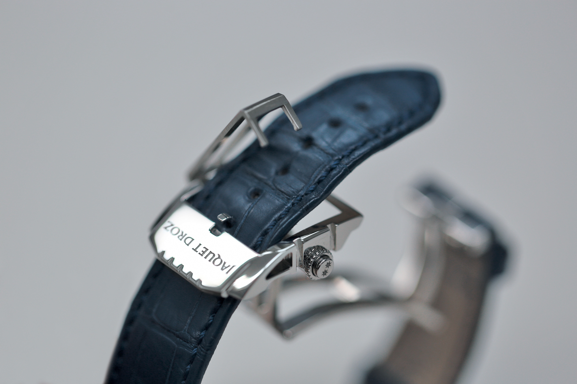 The complex buckle features a Jaquet Droz logo and a notched motif that echoes that of the bezel