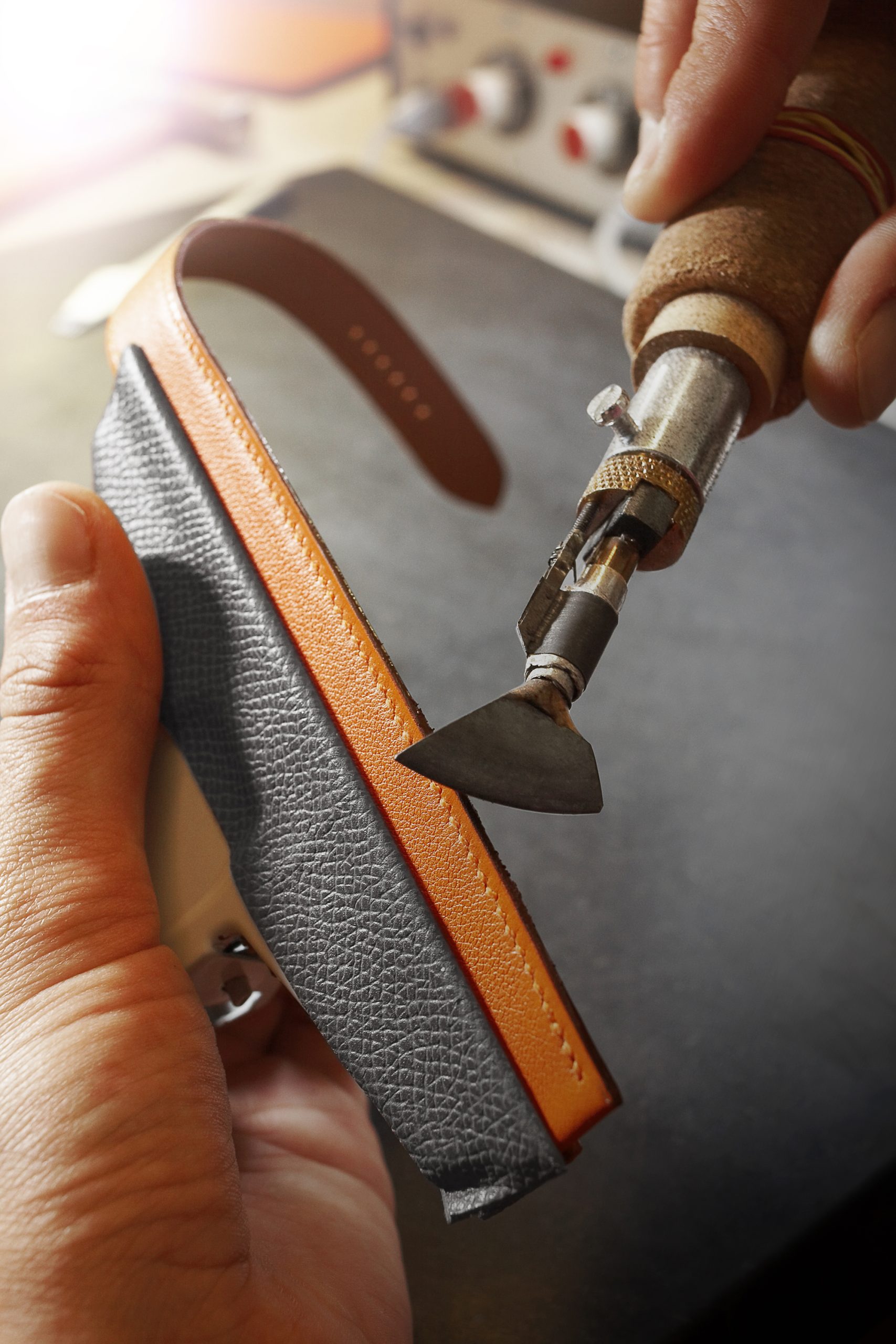The raw edges of the strap are brushed with sand paper and touched up with a layer of dye. A flat, warm, iron-like tool is then used to heat or glaze the edges. Each step is repeated until the look is perfectly uniform and the strap looks as if it came from a single piece of leather.