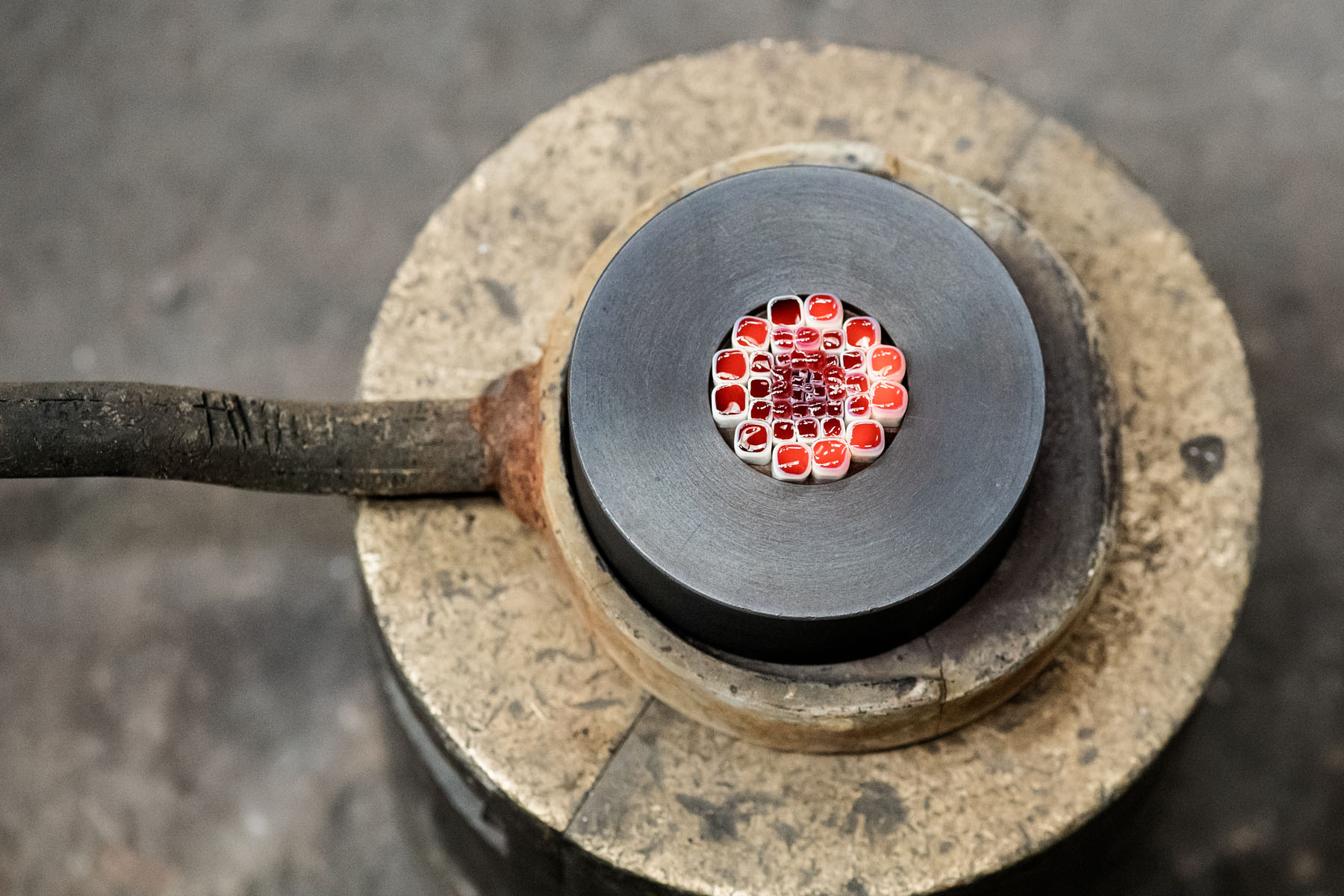 Making the Millefiori using patterns assembled from hot threads pulled from the molten material drawn from the mouth of the pots in the furnace. 
