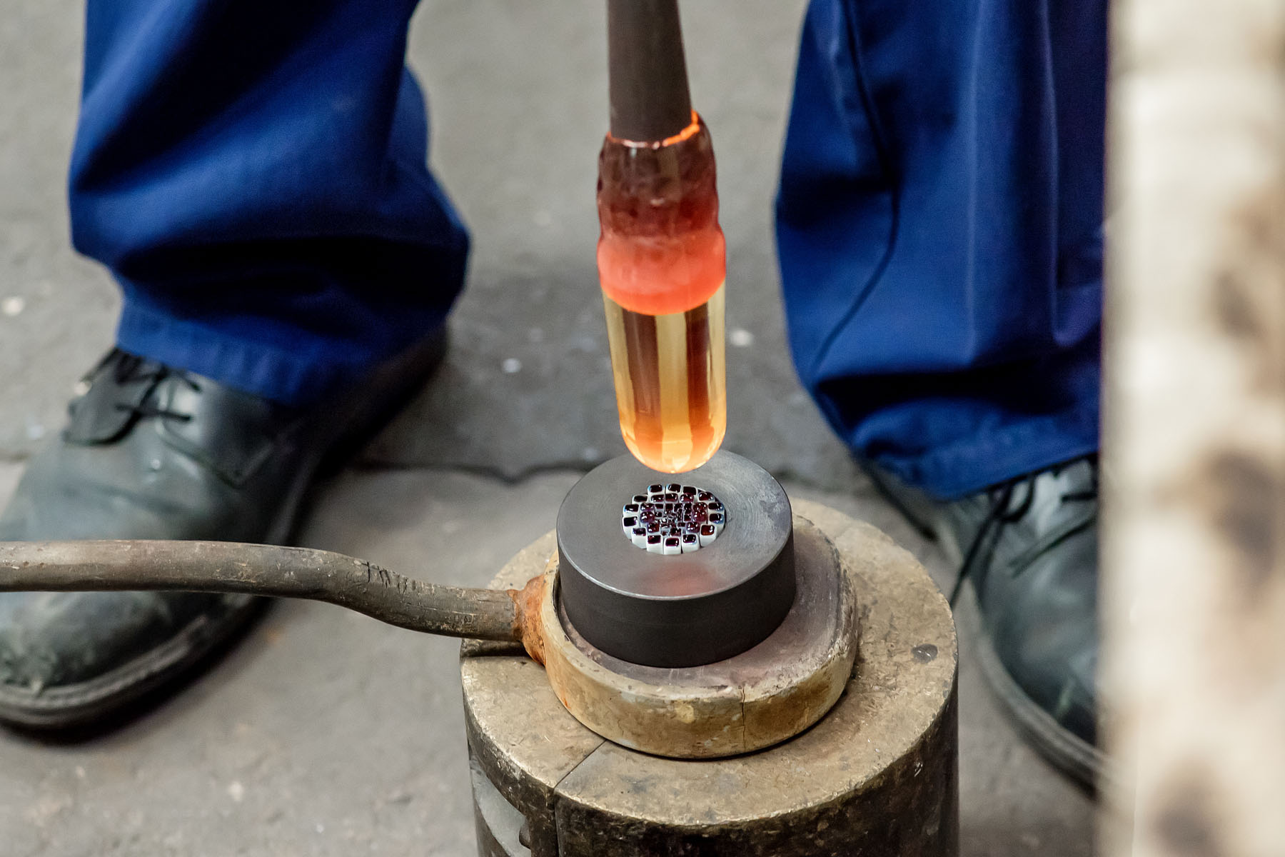 Making the Millefiori using patterns assembled from hot threads pulled from the molten material drawn from the mouth of the pots in the furnace. 