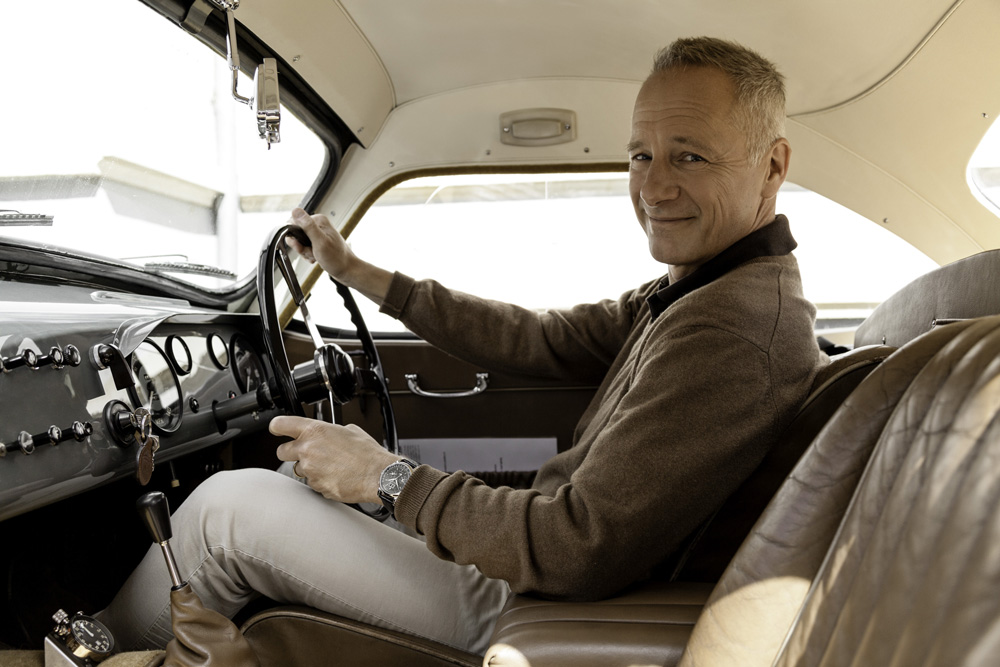 Combining two passions: Lange CEO Wilhelm Schmid wearing a DATOGRAPH PERPETUAL TOURBILLON behind the wheel of his 1957 Frazer Nash.