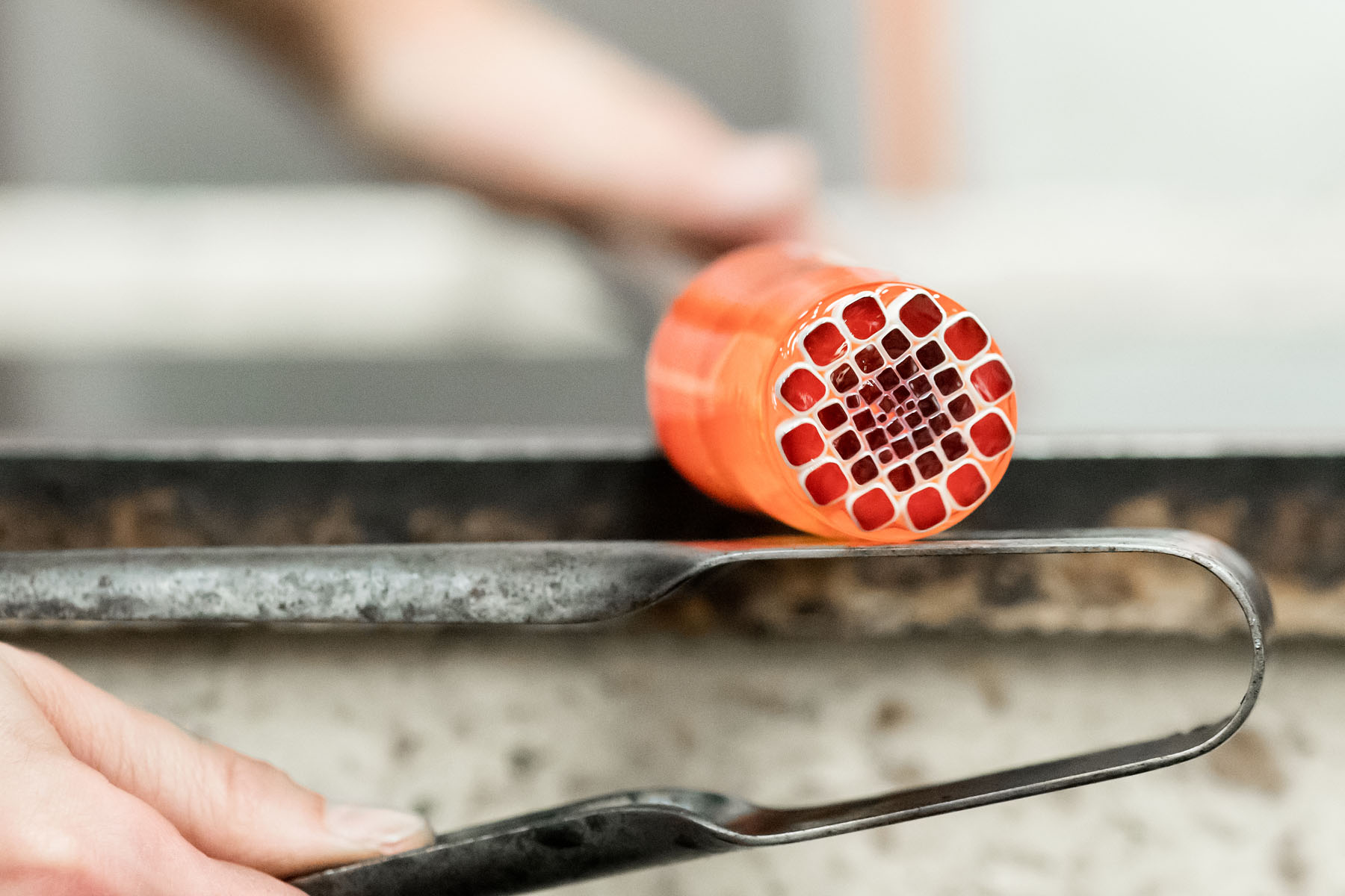 Making the Millefiori using patterns assembled from hot threads pulled from the molten material drawn from the mouth of the pots in the furnace. 