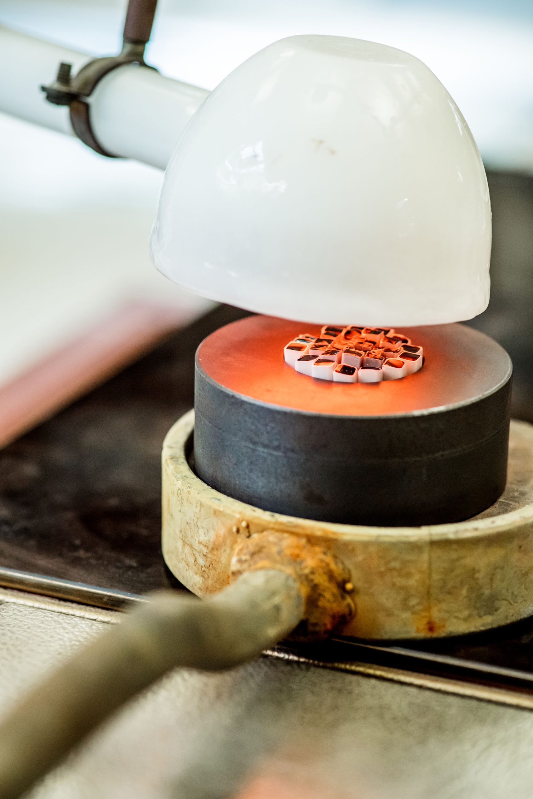 Making the Millefiori using patterns assembled from hot threads pulled from the molten material drawn from the mouth of the pots in the furnace. 